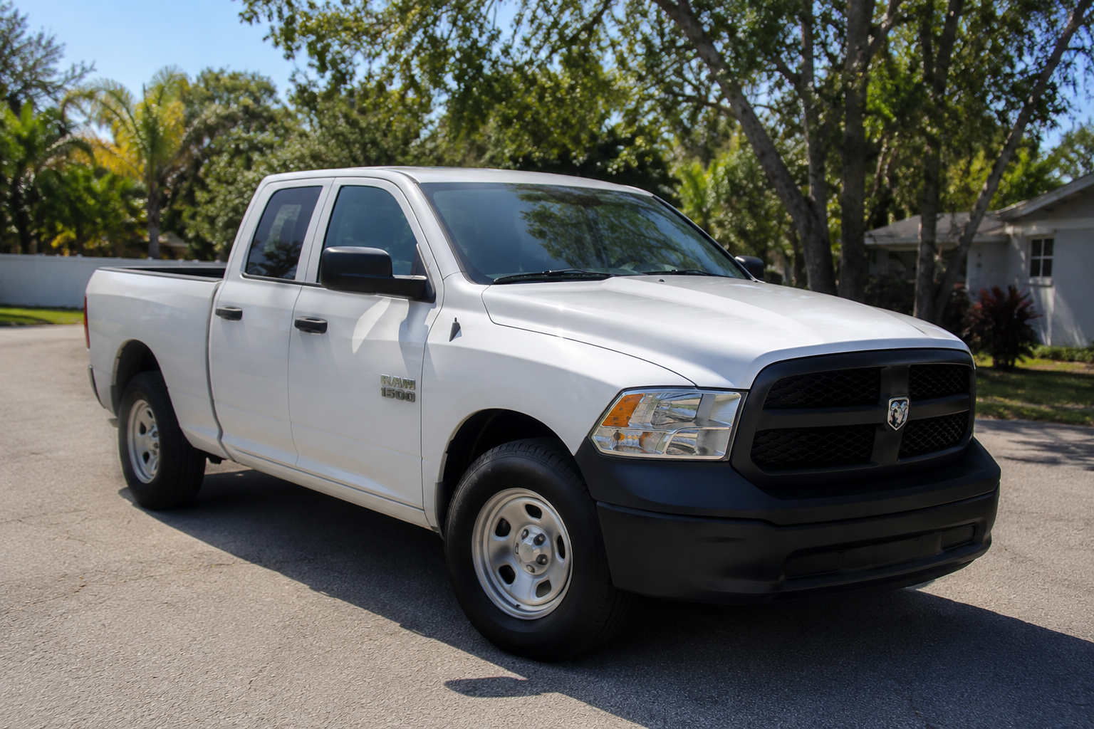 A clean white Ram 1500 crew cab pickup truck parked on a sunny Florida residential street, ready for local hauling work